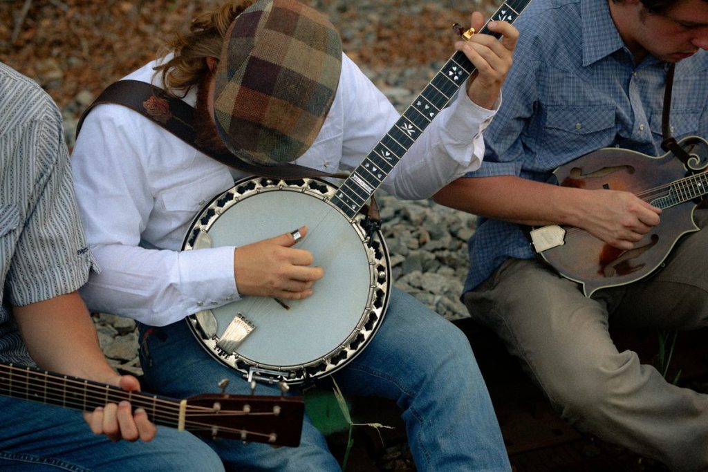 Banjo player picking with friends at an outdoor bluegrass jam