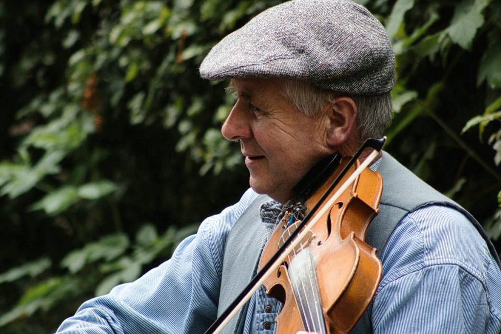 Folk fiddler in a flat cap playing the fiddle outdoors