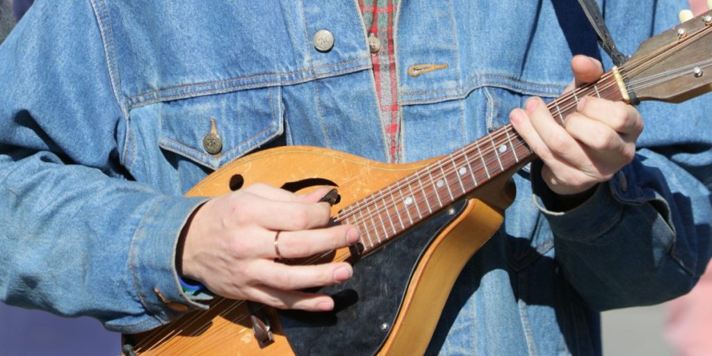 Musician in a denim jacket playing an A-style mandolin