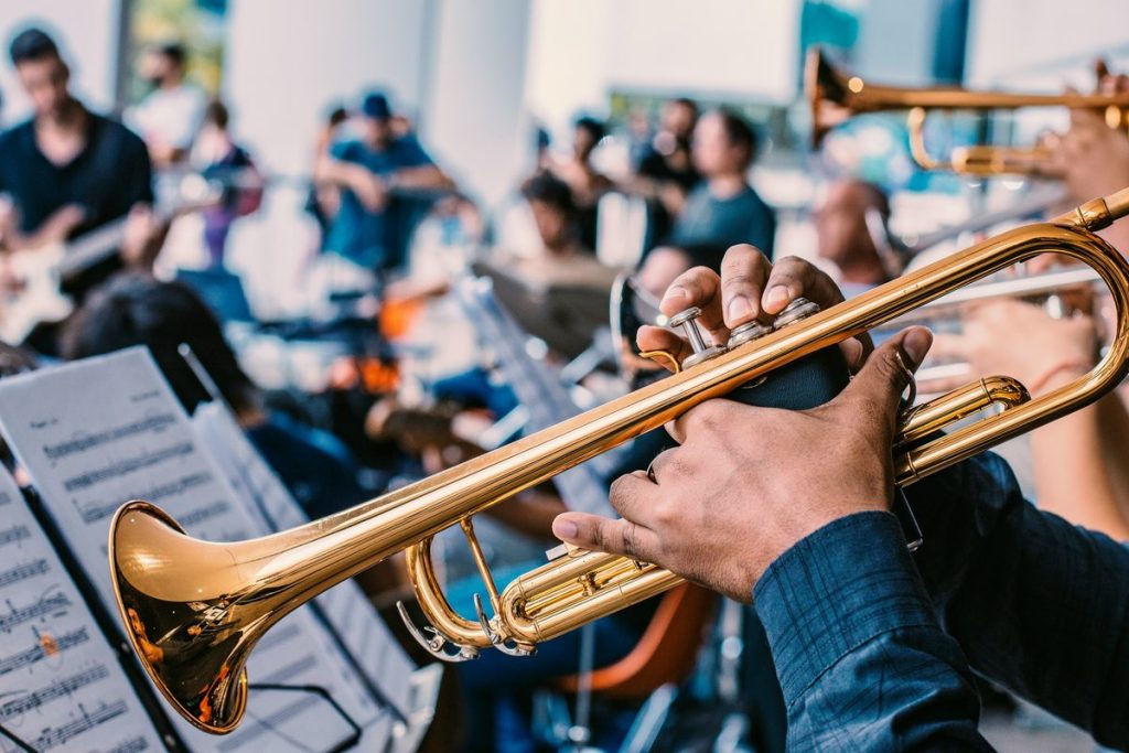 Trumpet player reading sheet music in a jazz band, a skill taught in trumpet lessons